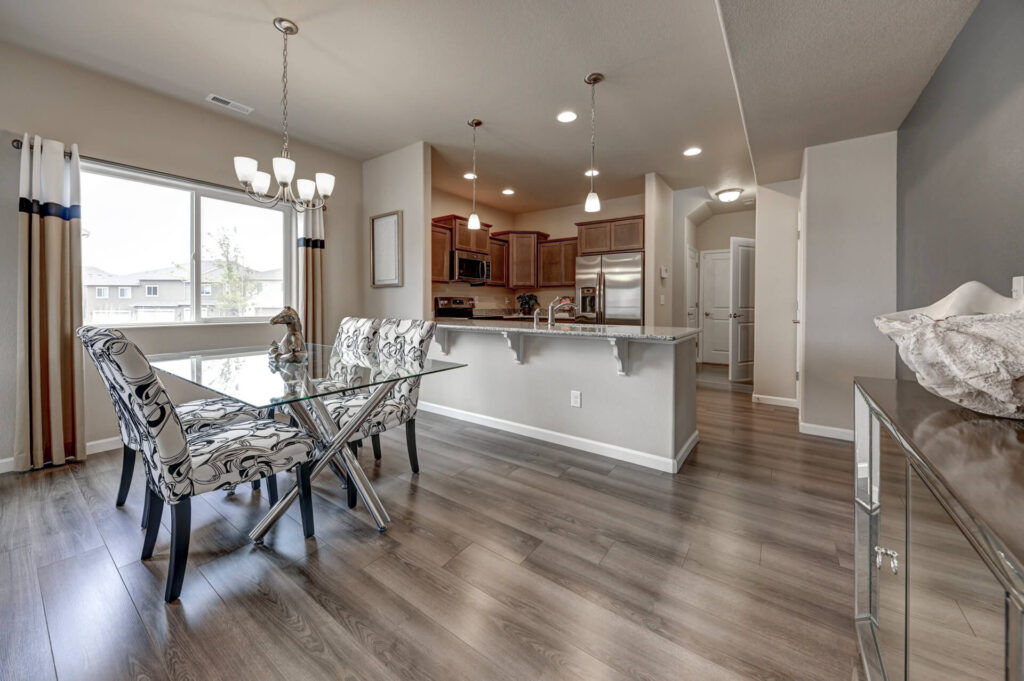 Open dining area beside a kitchen with a breakfast bar and wood cabinets