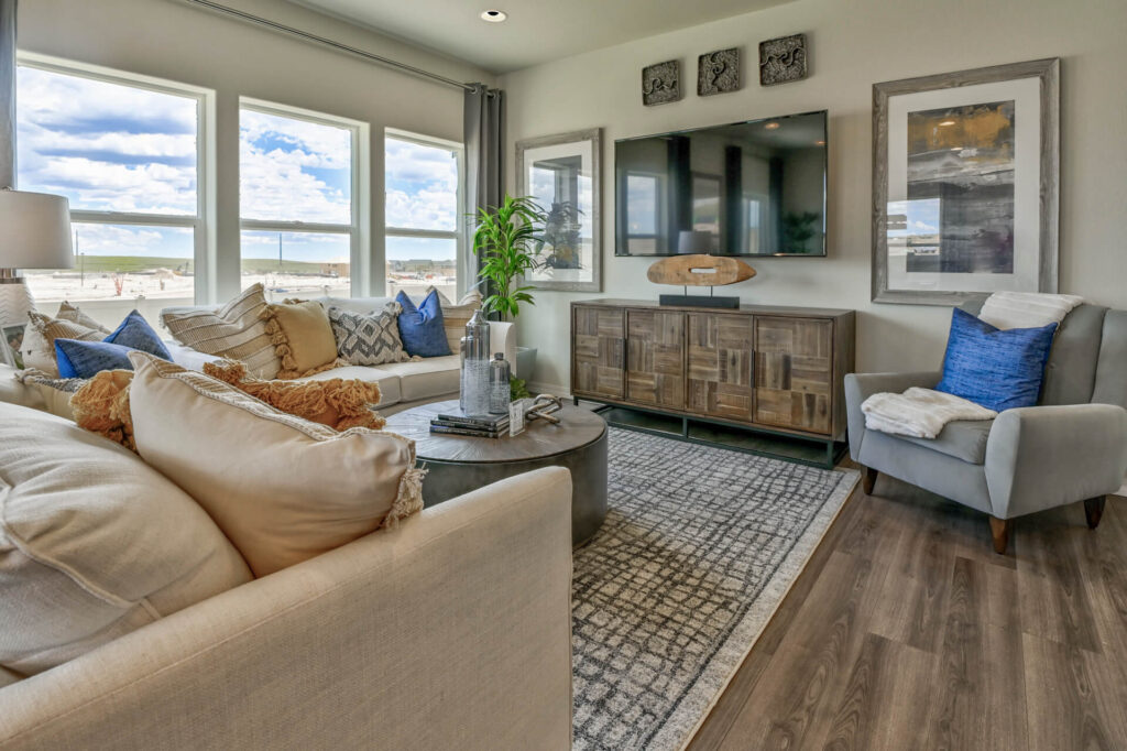 Living room with light sofas, patterned rug, wall-mounted TV and decorative pillows in neutral tones.