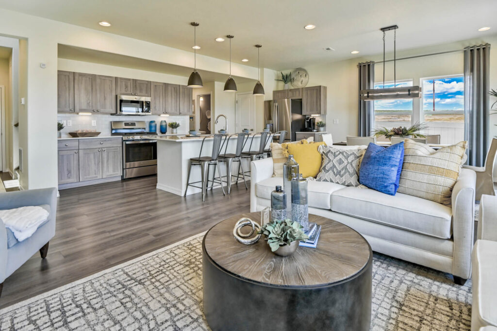Open-plan kitchen and living area with island, metal bar stools, and beige sofa.