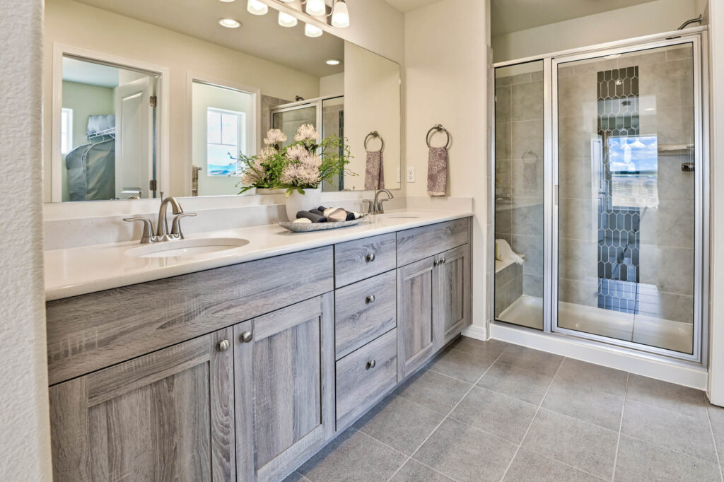 Bathroom vanity with double sinks, large mirror, and glass-enclosed tiled shower.