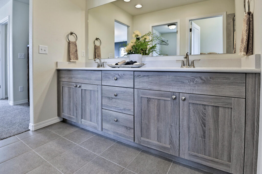 Wide-angle of bathroom vanity with mirror, sinks and doorway to adjacent room.