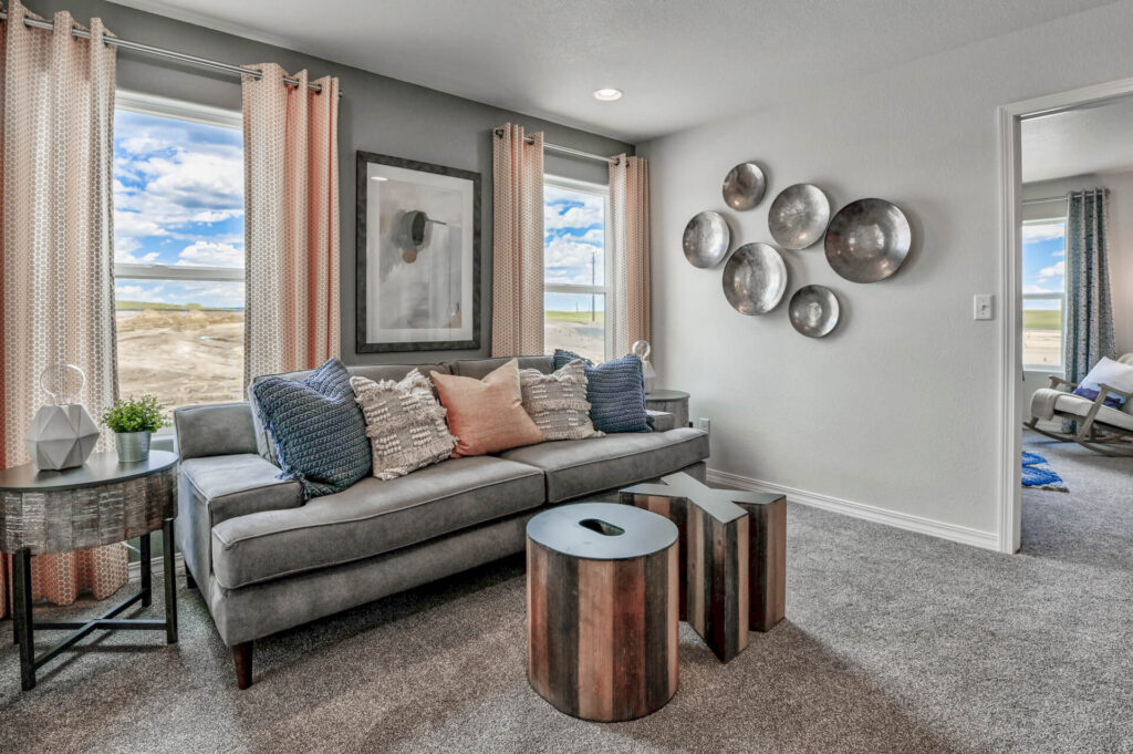 Bright sitting area with gray sofa, decorative pillows, round accent tables and wall art.