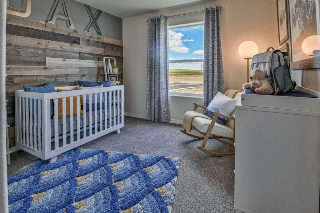 Nursery with white crib, textured wood accent wall, rocking chair, blue patterned rug, and window view.