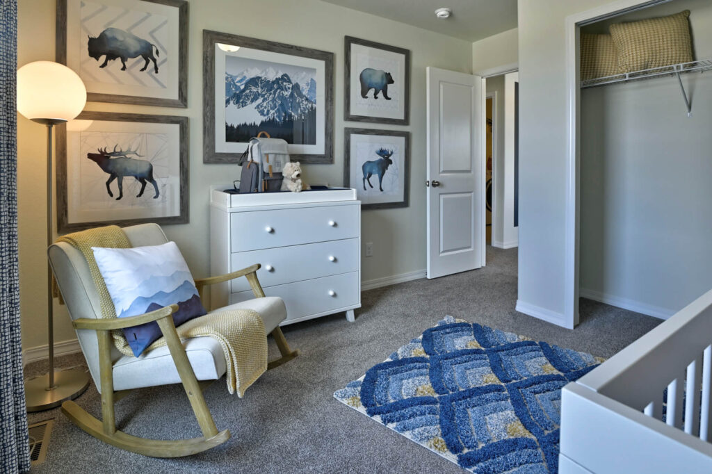 Small bedroom or nursery corner with rocking chair, white dresser, animal artwork, and open closet.