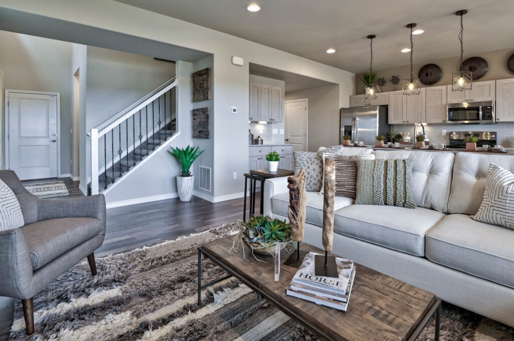 Open-plan living area with neutral sofa, armchair, textured rug, and wooden coffee table.