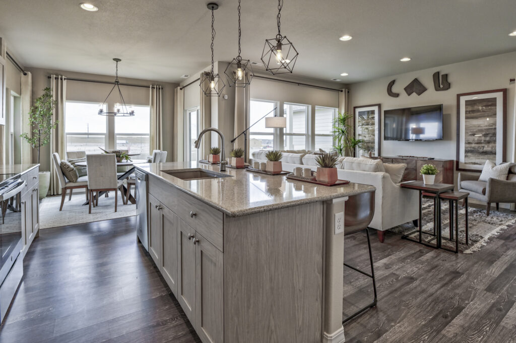 View from kitchen island showing sink, living area with sofa, and dining area by large windows.