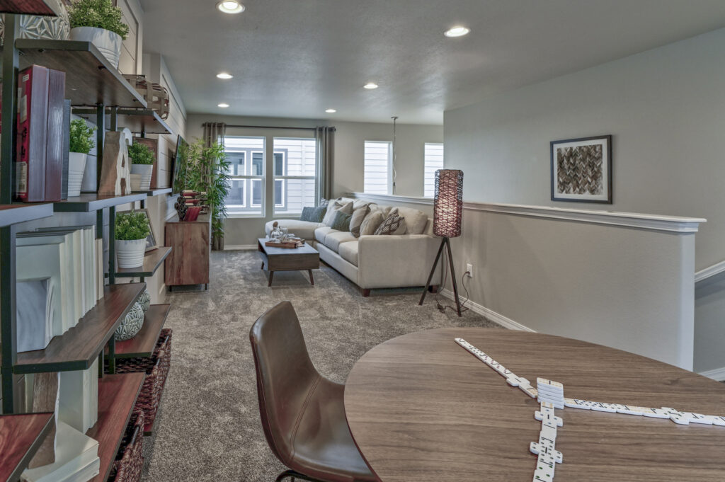 Long view of lounge area with round table in foreground and sofa under windows.