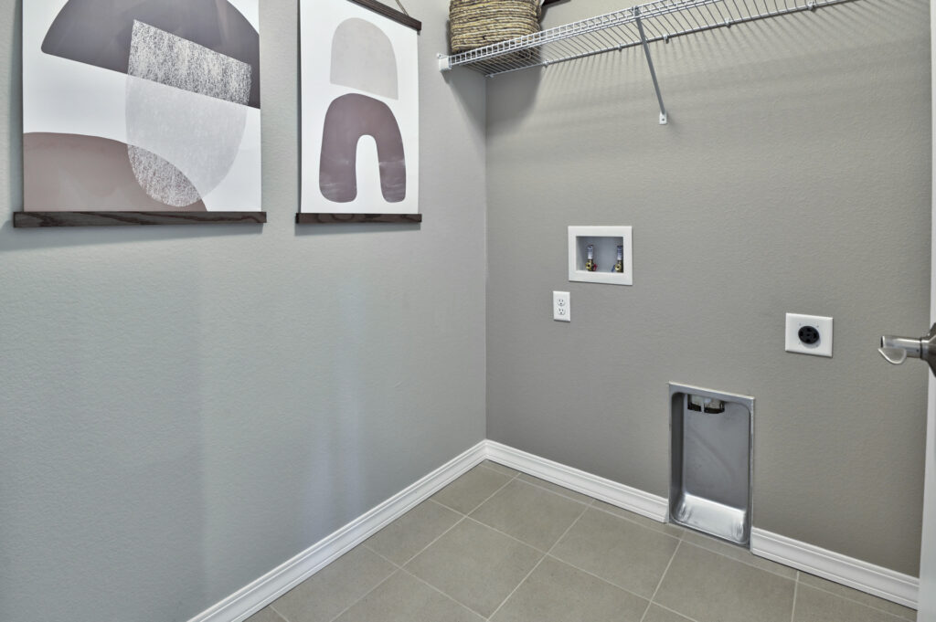 Laundry or utility room corner with tiled floor, shelving and washer/dryer hookups.