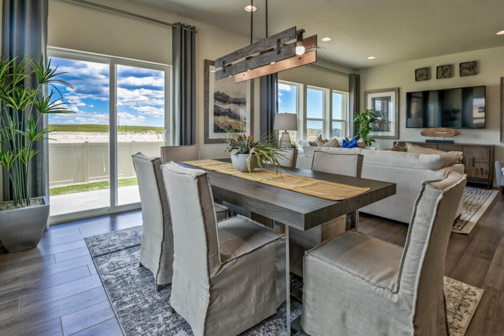Dining area with rectangular wooden table, six slipcovered chairs and sliding glass door to outdoors.