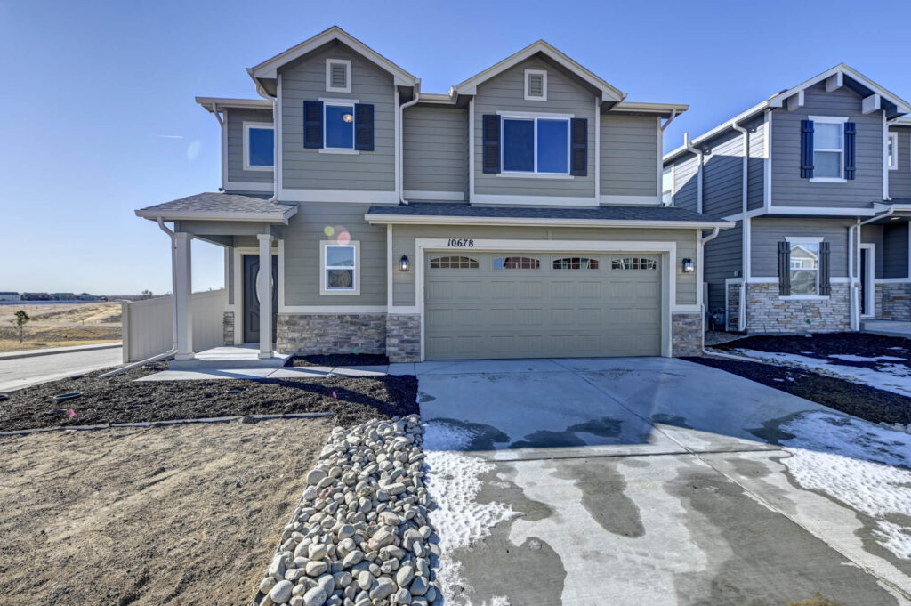 Front-facing two-story home with double garage, stone accents, and concrete driveway.