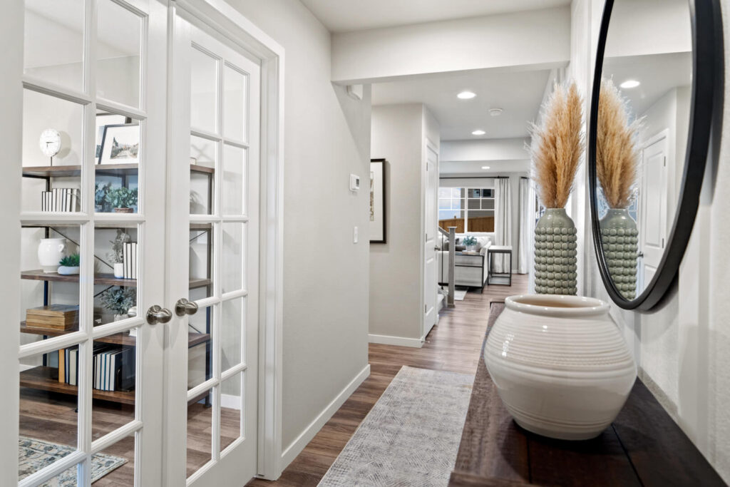 Interior entry hallway with glass French doors to a room and decorative console table with mirror.