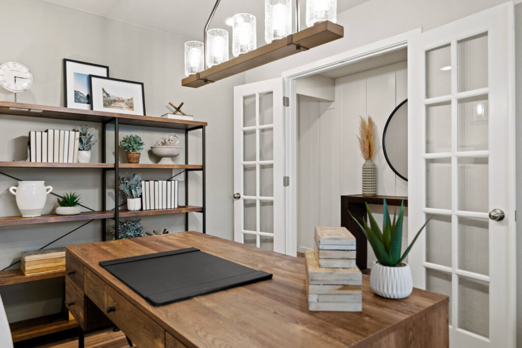 Home office with wooden desk, shelving unit, and French doors with glass panes.