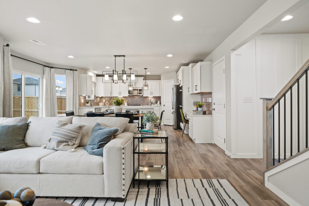 Open-plan living and kitchen area with sofa, dining table, and white cabinetry.