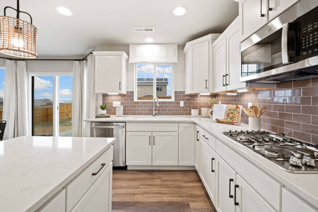 Kitchen island and workspace with gas cooktop, dishwasher, sink beneath window, and sliding door to backyard.