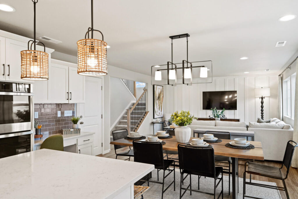 Open-plan kitchen and dining area with island, pendant lights, and a dining table set for six.