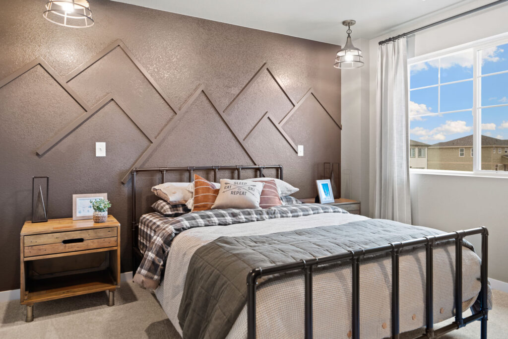 Bedroom with metal bed frame, brown textured accent wall featuring geometric trim, and bedside tables.