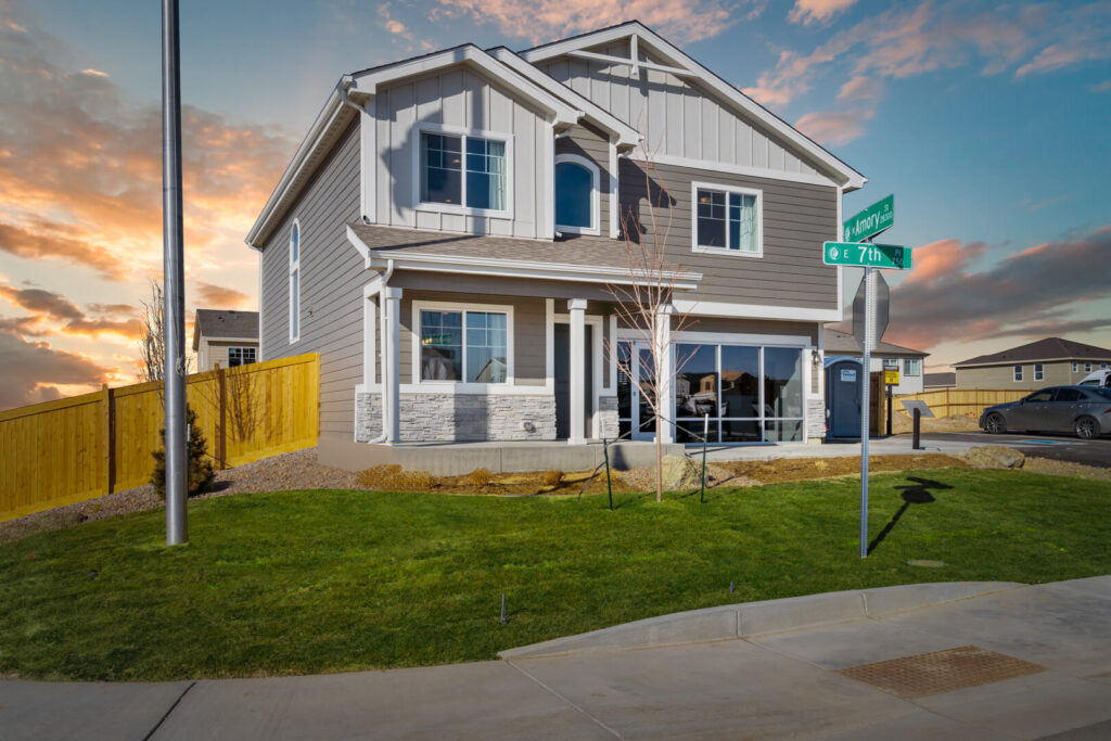 Corner-lot two-story house photographed from the street with lawn and street signs in foreground.