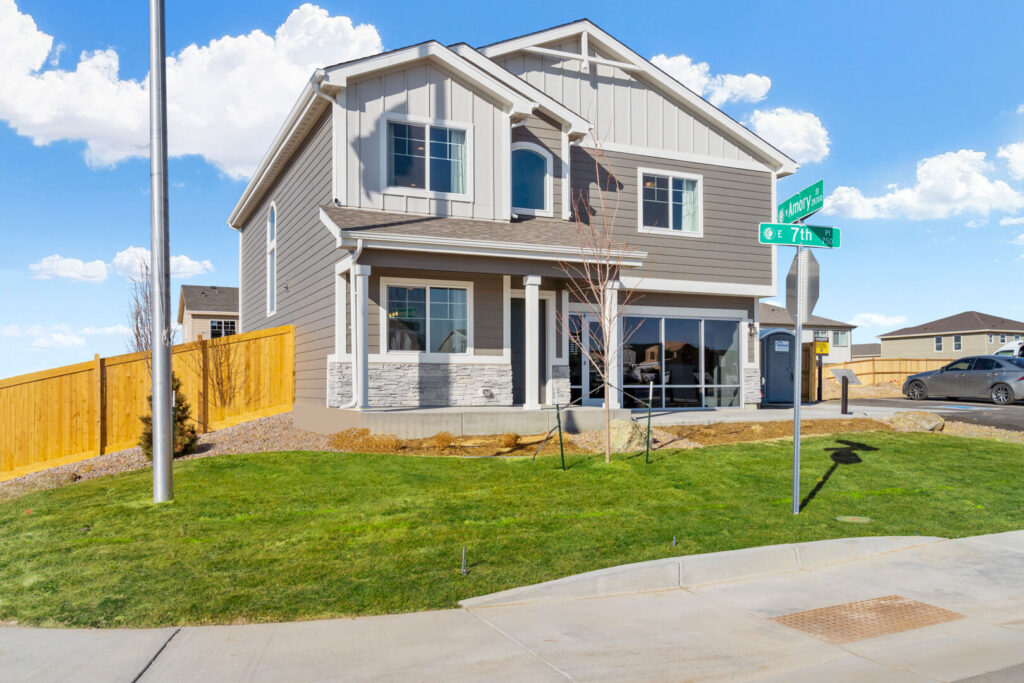 Corner two-story house with gray siding, porch columns and landscaped front lawn.