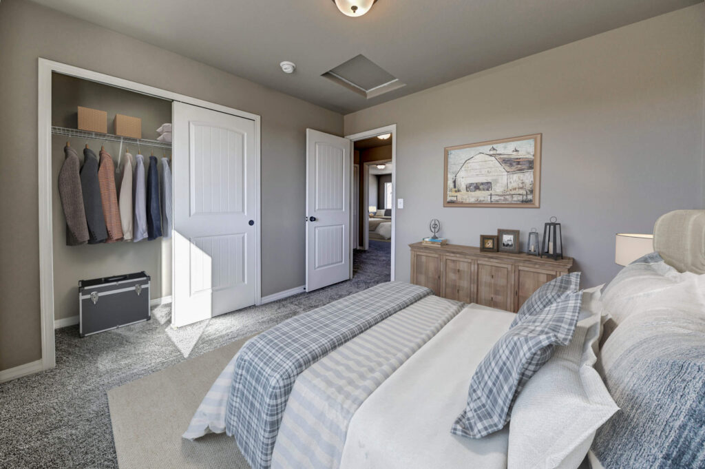 Bedroom view from bed showing open closet with hanging clothes and a doorway to a hallway.