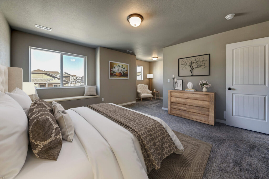 Wide-angle view of the same staged bedroom with bed, dresser, window seat, and seating nook.