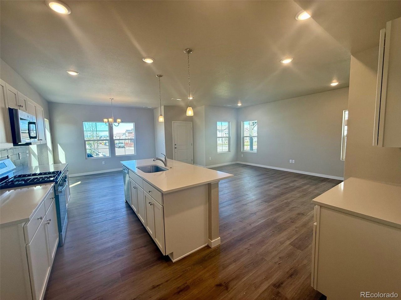 kitchen and living room with central island, pendant lights, recessed ceiling lights, and wood-look flooring