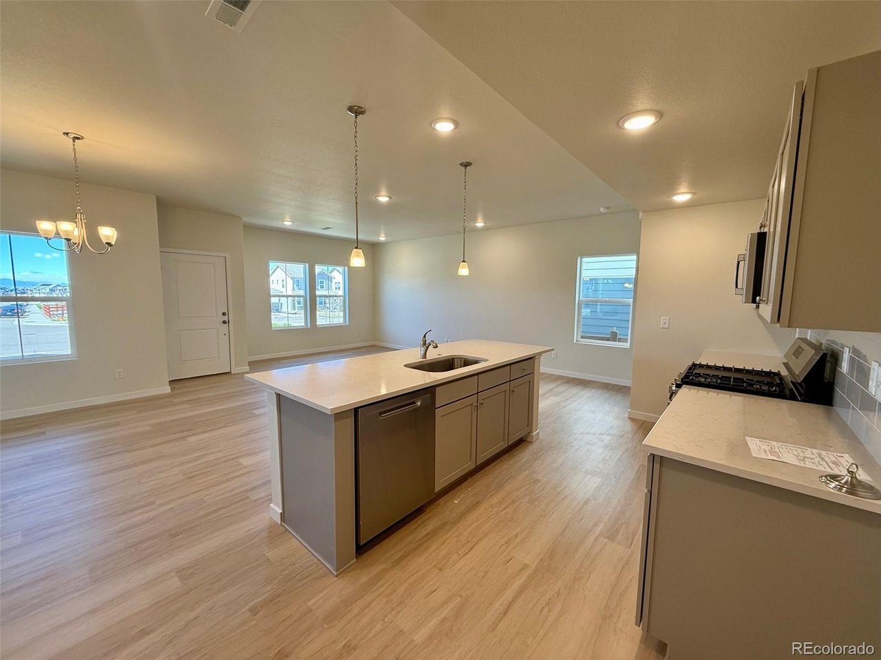 kitchen with central island and pendant lights, open plan to dining and living areas with multiple windows
