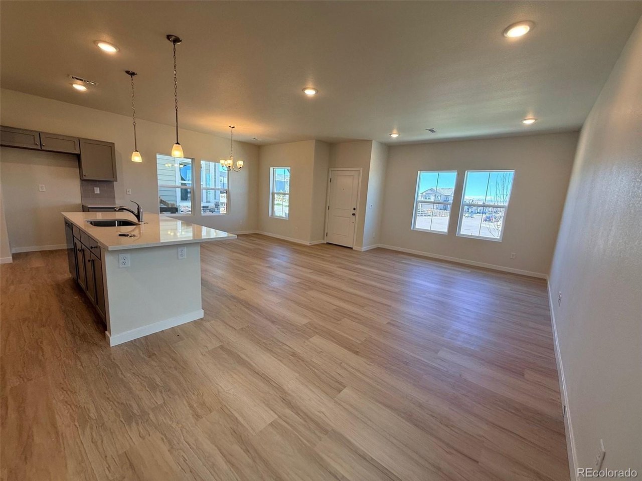 great room with open-plan kitchen island, pendant lights, and multiple windows