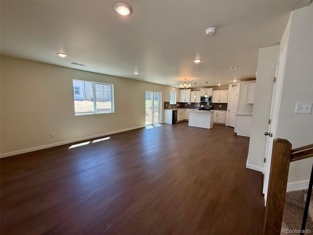 living room and kitchen with open-plan layout, recessed lights, sliding glass door, island, and dark wood-look flooring
